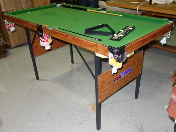 A 20th century small pool table with cues and balls.