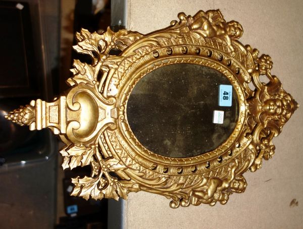 A pair of Continental 18th century style gilt metal wall mirrors, the frames relief cast with putti and female masks, surrounding oval mirror plates,