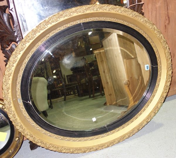 A gilt oval mirror with ebonised slip.