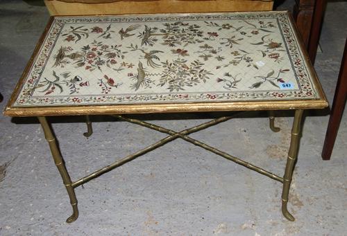 A brass coffee table with tapestry inset top.