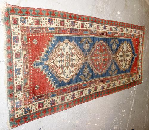 A West Persian rug, early 20th century, with three hooked medallions, an ivory ground, foliate border and minor borders, 93 x 218cm.