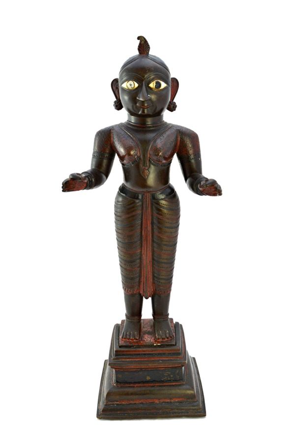 An Indian bronze figure of Krishna, 19th century, with inset ivory eyes and traces of red paint, raised on a stepped square base, 47.5cm high. Illustr