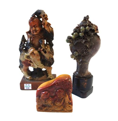 A Chinese carved soapstone tablet detailed with a deity and dog of Fo, 8cm high, another larger soapstone carved figure atop a dog of Fo, on a wooden