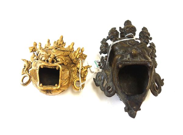 A Himalayan bronze open mouth model of a deity, 19th century, 17.5cm high, and a similar gilt bronze model of an open mouthed deity. (2)