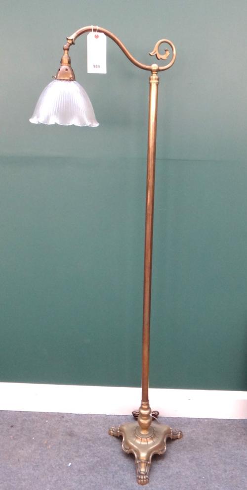 An Edwardian brass standard lamp, with scroll arm and frosted glass shade on a triform base and lion paw feet, 166.5cm high.