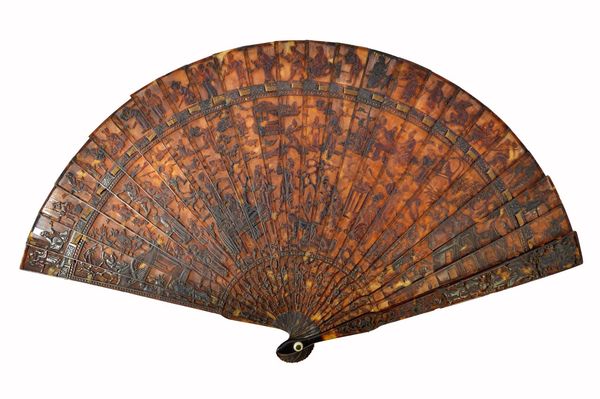 A Canton tortoiseshell fan, 19th century, carved all over with Oriental figures (a.f), the stick guard 19cm long. Illustrated