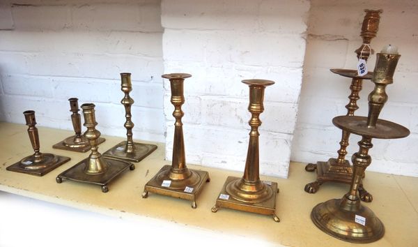 A Continental brass candlestick, early 19th century, with wide octagonal drip pan over a tapering square base and lion paw feet 39cm high, a pair of 1