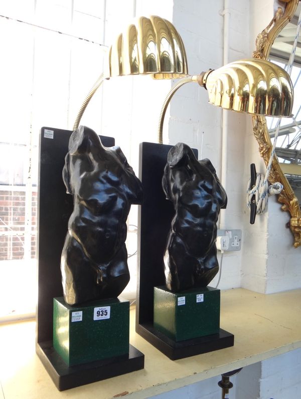 A pair of modern figural table lamps, each with an ebonised male torso atop a faux malachite plinth, with adjustable brass arm and shade, the backplat