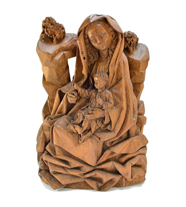 A Tyrolean style carved limewood group, 19th century, detailed with a mother and child beneath a naturalistic bocage, 46cm high. Illustrated