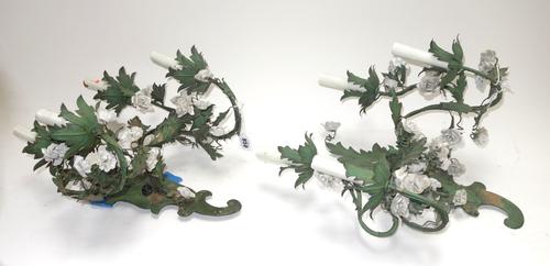 A pair of modern tôle peinte four branch wall appliques, each of painted foliate design, with porcelain flower head finials against a shaped backplate