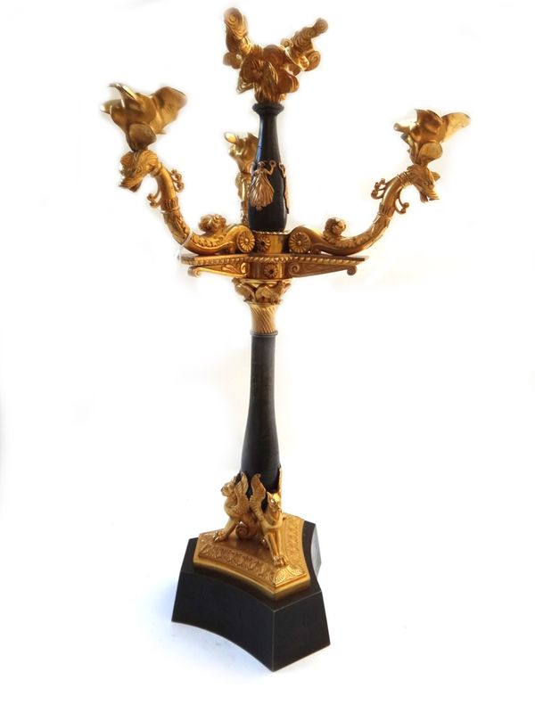 A pair of gilt and patinated bronze four branch candelabra, each of Empire style, the swan neck branches over three griffin supports and a triform bas