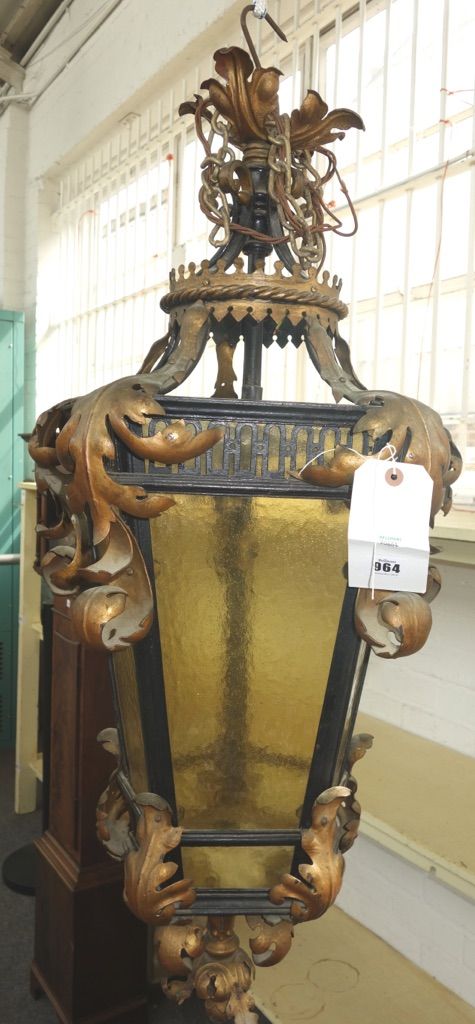 A wrought iron hexagonal hall lantern early 20th century, with amber mottled glass panels and sheet brass foliate embelishments.  95cm high