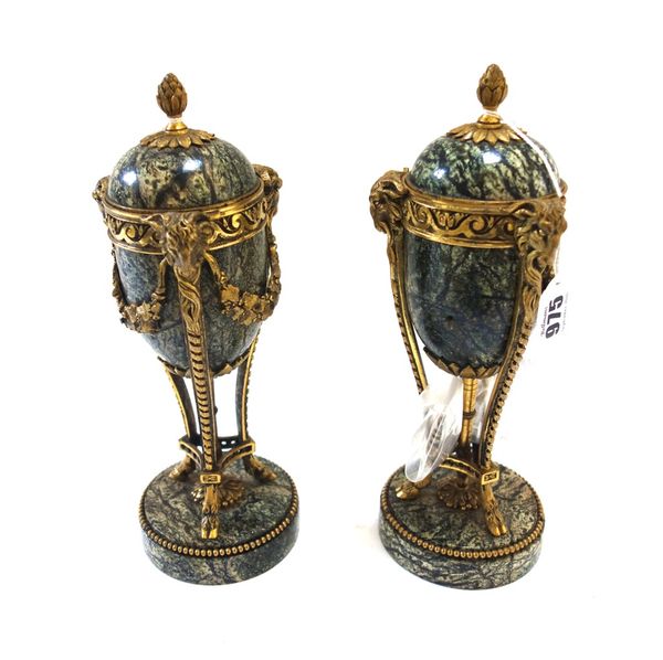 A pair of marble and ormolu mounted cassolettes, circa 1900, each domed cover over a triform ormolu frame cast with ram's head masks, on a circular be