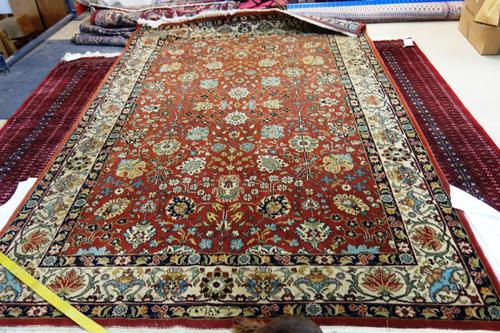 A Romanian rug, the madder field with all over flowers and palmettes, an ivory flower and vine border, 304 x 210cm.