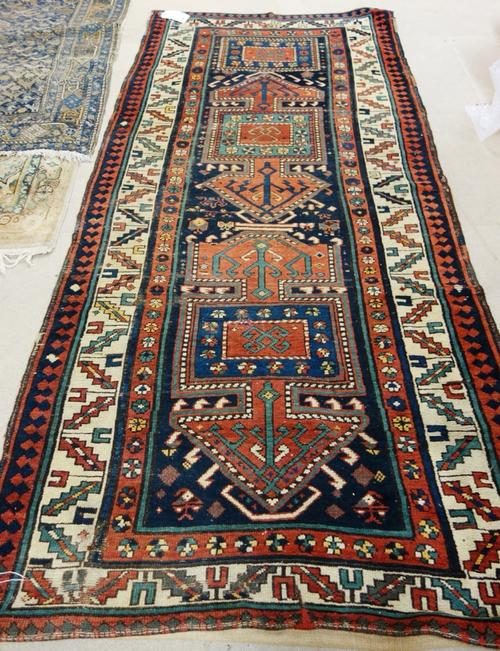 A Sewan Kazak runner, Caucasian, the indigo field with two madder medallions and extra indigo medallion, minor flowerheads, an ivory tulip and leaf bo