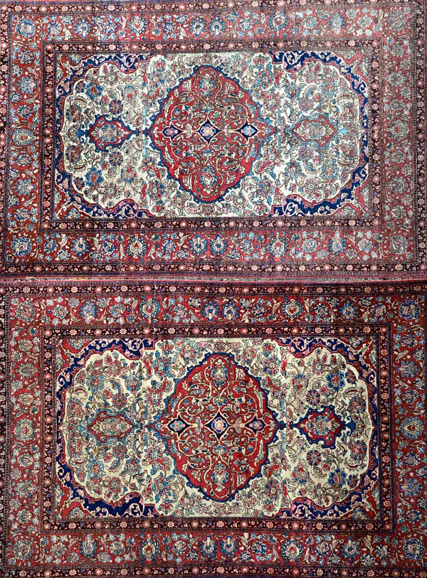 A pair of Esfahan rugs, Persian, each ivory field with a bold madder lobed medallion, indigo and madder spandrels, all with floral sprays, a madder pa
