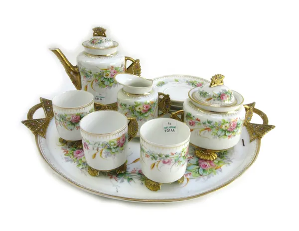 An English porcelain part tea service, late 19th century, decorated with flowers against a white ground, the gilt handles and feet shaped as jeweled f