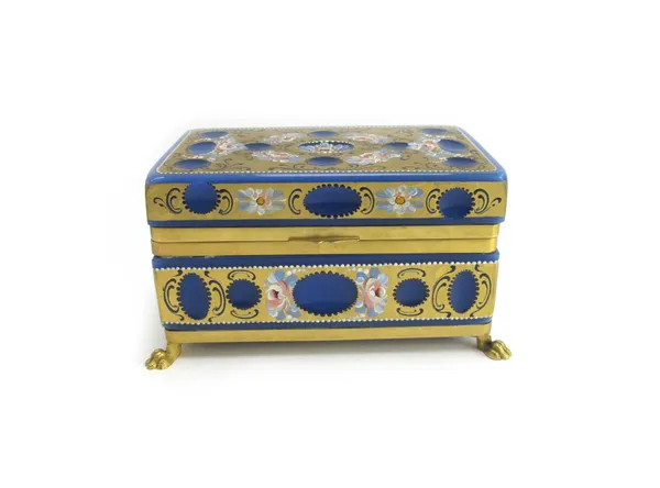 A blue glass casket, 20th century, of rectangular form, gilt decorated and painted with flowers, on brass lions paw feet, 20cm wide.