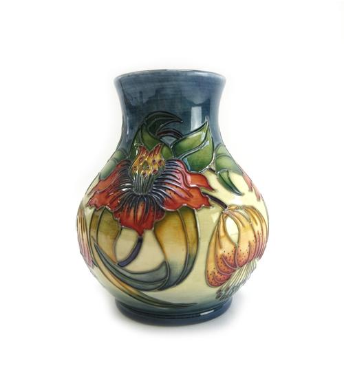 A Moorcroft pottery vase, 'Arun Lilly' pattern, circa 1998, tube line decorated with flowers against a blue and cream ground, impressed and painted ma