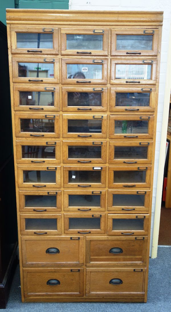 A 20th century oak haberdashery cabinet, with ten rows of three graduated glass fronted drawers, 89cm wide x 192cm high.