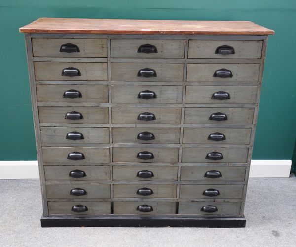 A painted pine bank of three rows of nine drawers, on plinth base, 125cm wide x 119cm high.