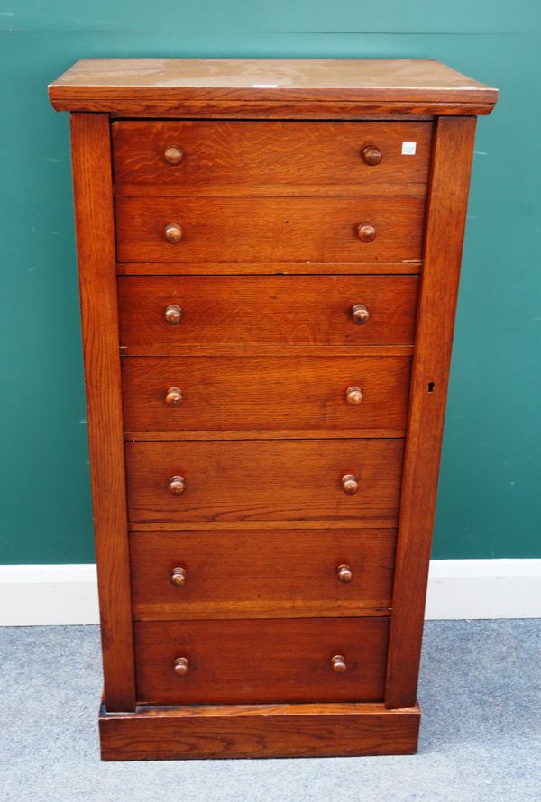 A Victorian oak Wellington chest, with seven graduated drawers enclosed by locking bar, 61cm wide x 119cm high.