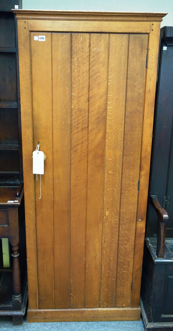 Heals; an oak hanging cupboard, with single plank door on a plinth base, 73cm wide x 176cm high.Footnote: this cupboard is listed in 'Middle Class Fur