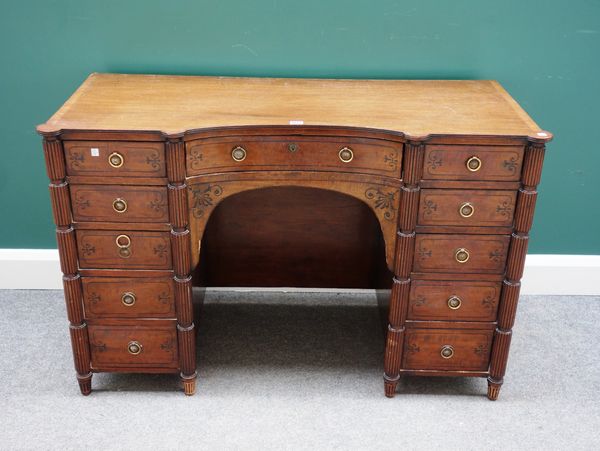 A George IV inlaid mahogany concave fronted kneehole writing desk, with eleven frieze drawers divided by fluted columns, 120cm wide x 52cm deep.