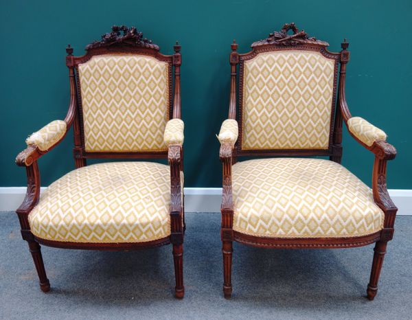 A pair of Louis XVI style carved walnut fauteuils, with arrow, quiver and torch crest rail, each 62cm wide x 100cm high (2).