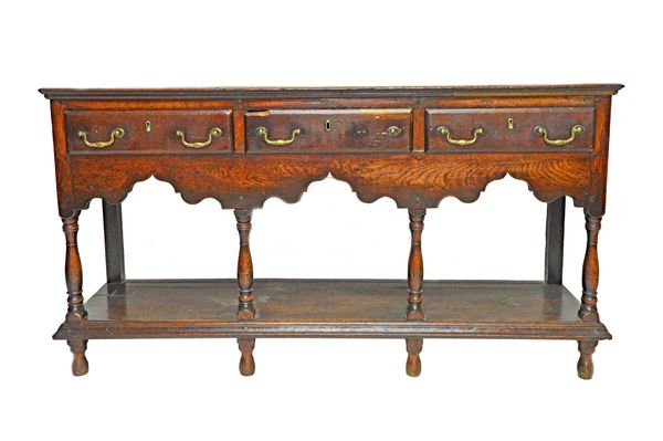 An early 18th century oak dresser base of small proportions, with three drawers over shaped frieze and pot board undertier, on baluster supports, 144c