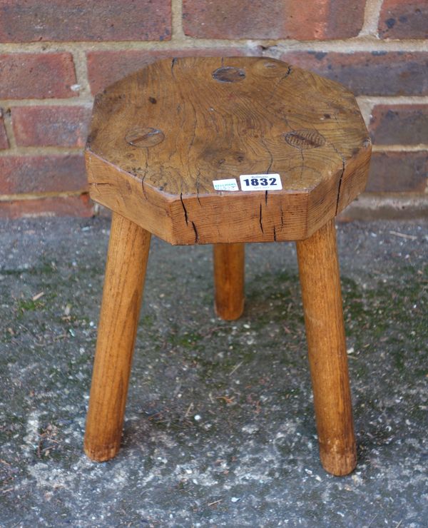 A milking stool with octagonal elm top on three staked ash supports, 38cm high.