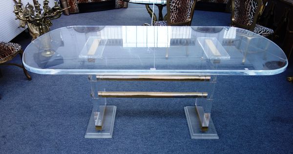 A 20th century acrylic and lacquered brass desk, with oval top on trestle supports, 90cm x 190cm.