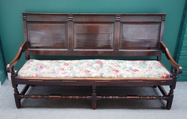 An early 18th century oak triple panel back open arm settle, on block and turned supports, 181cm wide x 101cm high.