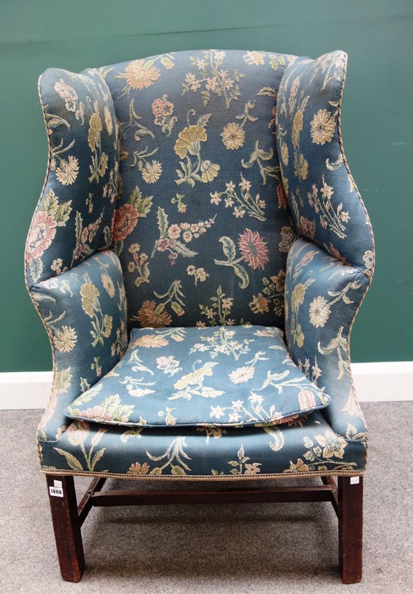 An early 18th century shaped wingback armchair, on block mahogany supports, 76cm wide x 118cm high.