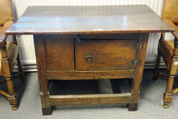 A 17th century oak food cupboard, with plank top over single door, on canted block supports united by perimeter stretcher, 110cm wide x 71cm high.