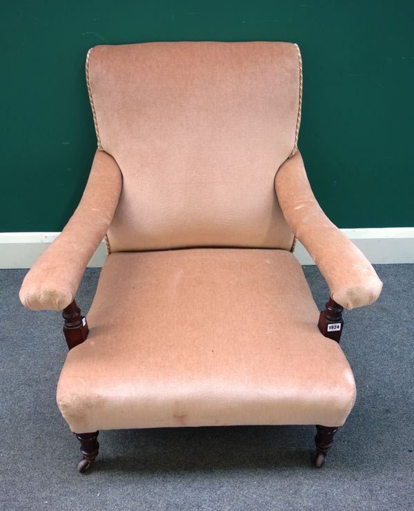 A late Victorian mahogany framed low deep armchair with open arms, turned tapering legs with brass cappings and castors stamped 'Hamptons London', 77c