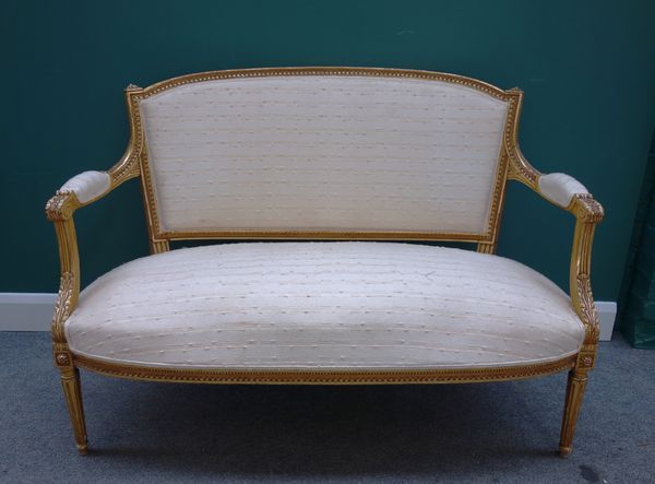 A Louis XVI style gilt framed open arm sofa, with bow seat on tapering fluted supports, 130cm wide x 93cm high.