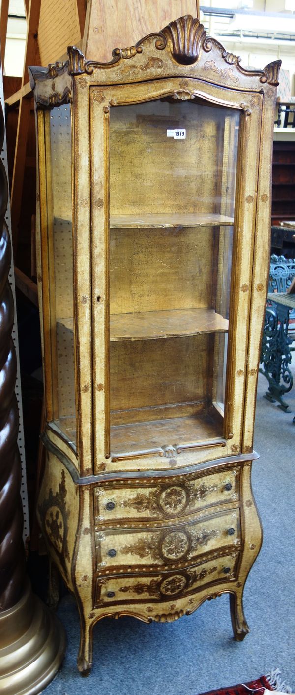 An early 20th century Italian cream painted parcel gilt display cabinet, on bombe three drawer base, 65cm wide x 180cm high.