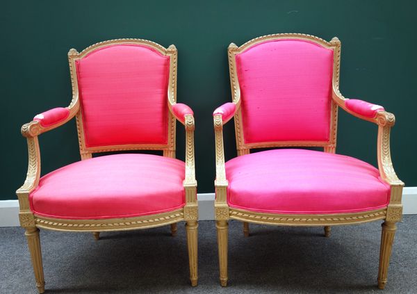 A pair of Louis XVI style pink upholstered open armchairs, with carved frames on tapering fluted supports, 64cm wide x 94cm high   (2).