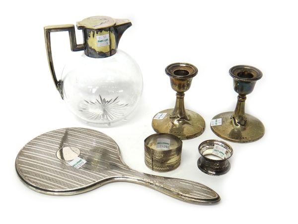 Silver and silver mounted wares, comprising; a hand mirror, a pair of candlesticks and two napkin rings, also a silver plated metal mounted claret jug