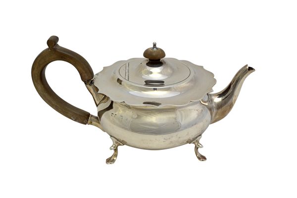 A silver teapot, of squat circular form having a shaped rim, raised on four pad feet, with wooden fittings, Birmingham 1923, gross weight 533 gms.   I