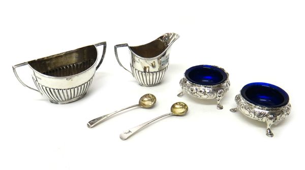 Silver, comprising; two similar circular salts, with floral embossed decoration, each raised on three feet, London 1857 and 1859, with blue glass line