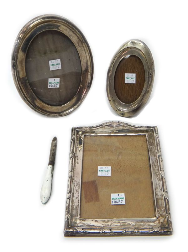 A silver mounted shaped rectangular photograph frame, Birmingham 1920, two silver mounted oval photograph frames, Birmingham 1913 and Birmingham 1918