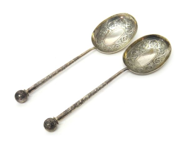 A pair of Victorian silver dessert or fruit serving spoons, the curved oval bowls with scroll engraved decoration, the similarly decorated handles hav