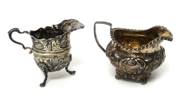 A George IV silver milk jug, with floral, foliate and scroll embossed decoration, raised on four floral feet and having a gadrooned rim, London 1824 a