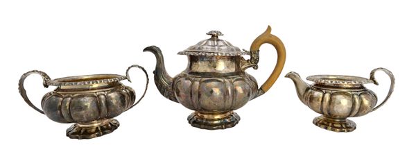 A George IV silver three piece tea set, of compressed melon fluted form, comprising; a teapot with a wooden handle, a twin handled sugar bowl and a mi