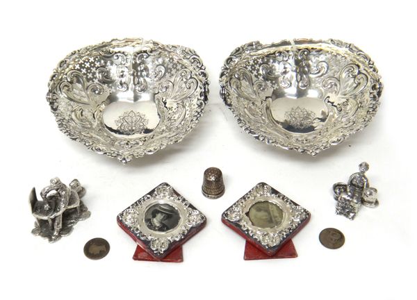 A pair of Sterling heart shaped bonbon dishes, each with embossed and pierced decoration and with a swingover handle, two silver cast models of figure