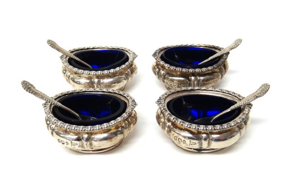 A set of four late Victorian silver salts, each of oval form with decorated rims, by Walker & Hall, Sheffield 1895, with blue glass liners and four si