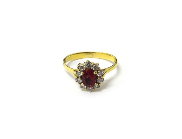 An 18ct gold, ruby and diamond set eleven stone cluster ring, claw set with the oval cut ruby at the centre, in a surround of ten circular cut diamond