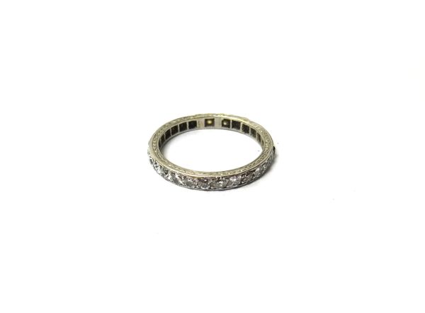 A diamond set full eternity ring, mounted with cushion shaped diamonds (one colourless gem replacement), the mount decorated with engraved sides, ring